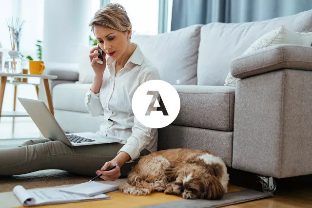 A woman works remotely from home with her dog
