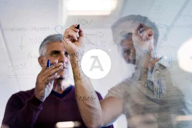 Two office workers planning together on a whiteboard