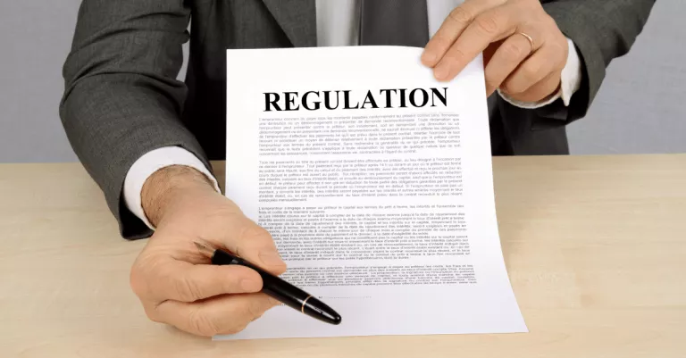 A lawyer holding a sheet of paper that says "regulation"