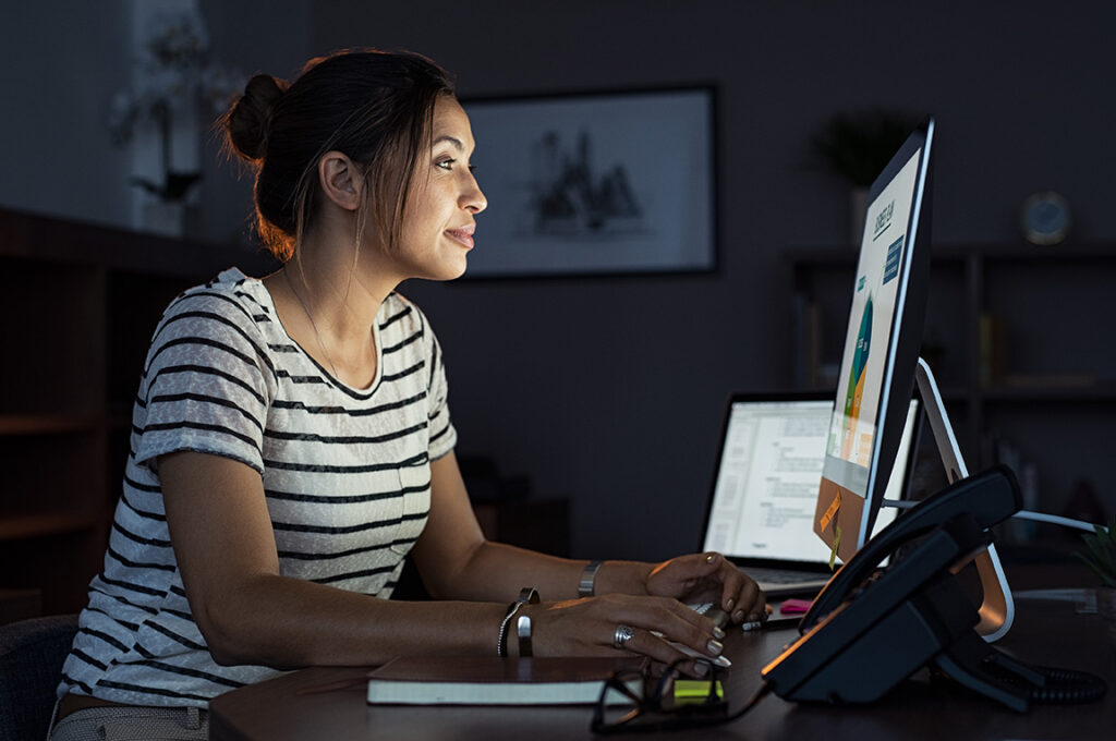 Young businesswoman in casual clothing working on desktop computer making business plan.