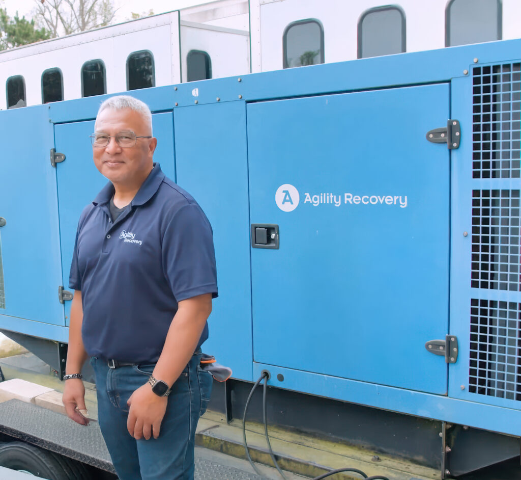 An Agility employee stands in front of a generator